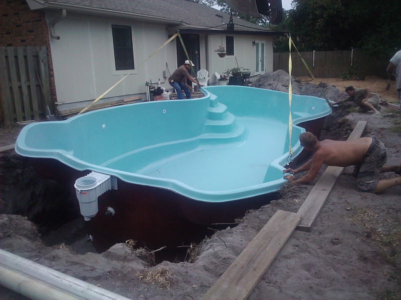 Fiberglass pool being installed in backyard